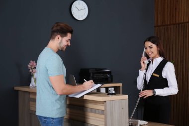 Müşteride resepsiyonda kayıt resepsiyonisti lobide telefonda konuşurken