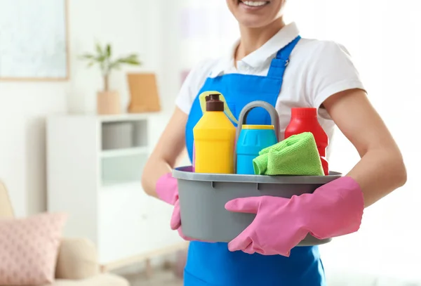 Mulher com bacia de detergentes na sala de estar, close up. Serviço de limpeza — Fotografia de Stock