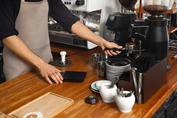 Barista pouring milled coffee from grinding machine into portafilter at bar counter, closeup — Stock Photo, Image