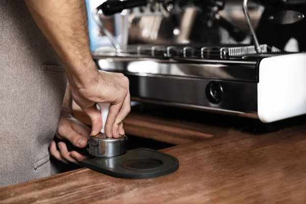 Barista tamping milled coffee in portafilter at bar counter, closeup. Space for text — Stock Photo, Image