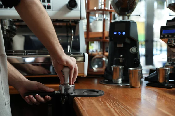 Barista tamping coffee in portafilter at bar counter, closeup. Space for text — Stock Photo, Image