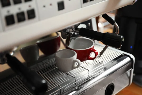 Modern coffee machine with cups in cafe — Stock Photo, Image