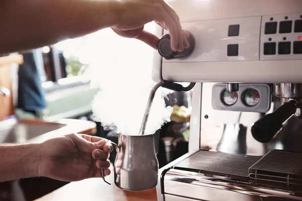 Barista steaming milk in metal jug with coffee machine wand at bar counter, closeup — Stock Photo, Image