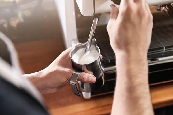 Barista frothing milk in metal pitcher with coffee machine wand at bar counter, closeup — Stock Photo, Image