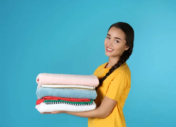 Mutlu genç kadın renkli arka plan üzerinde temiz çamaşır tutan — Stok fotoğraf