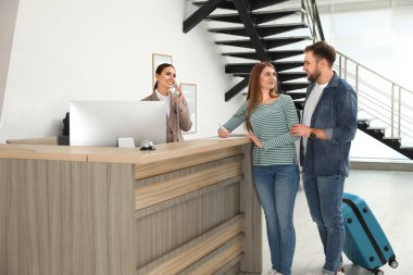 Modern otel masasında müşterileriyle çalışan profesyonel resepsiyonist