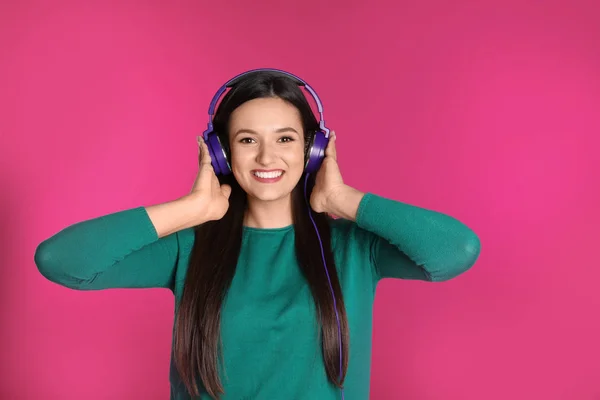 Attraktive junge Frau genießt Musik in Kopfhörern auf farbigem Hintergrund — Stockfoto