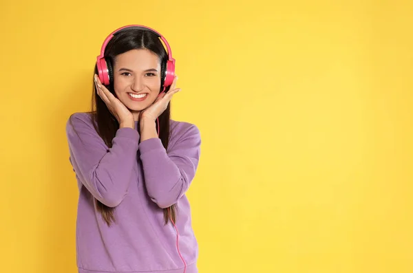 Attraktive junge Frau genießt Musik in Kopfhörern auf farbigem Hintergrund. Raum für Text — Stockfoto