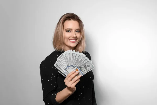 Portrait of young woman with money fan on light background — Stok Foto