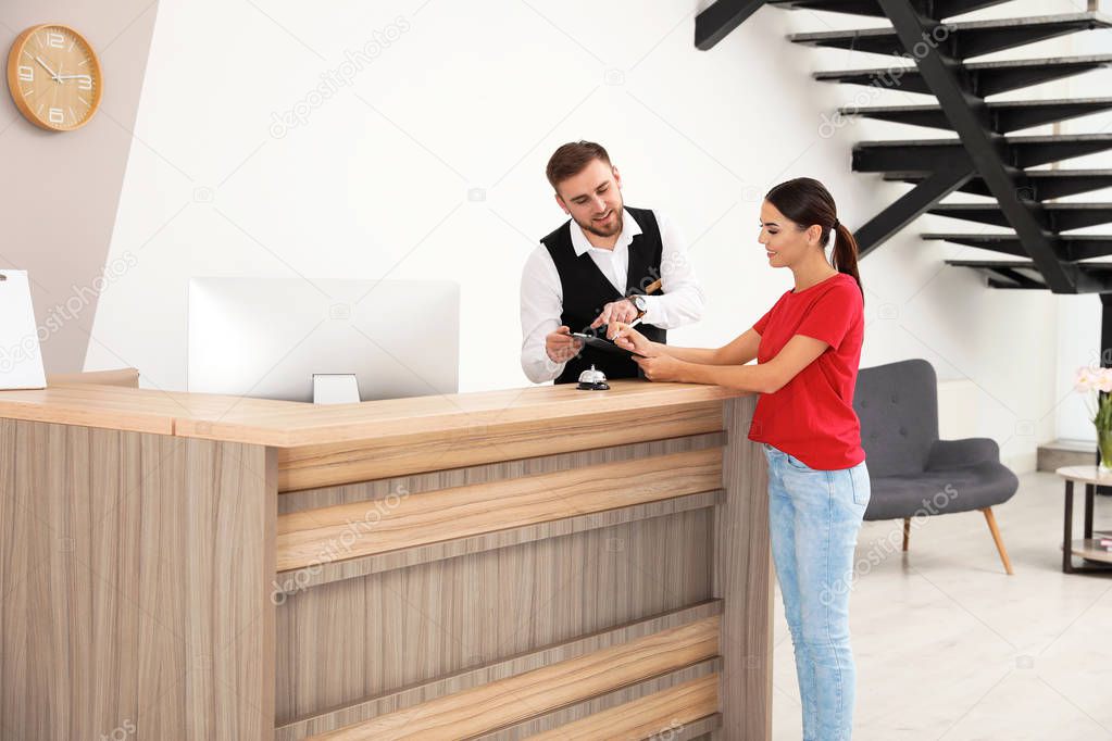 Professional receptionist working with client at desk in modern hotel