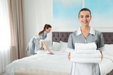 Otel odasında temiz havlu yığını olan oda hizmetçisi. Metin için alan