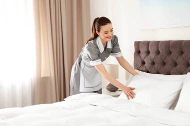 Otel odasında yatak yapma genç Oda hizmetçisi