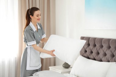 Otel odasında yatak yapma genç Oda hizmetçisi. Metin için yer