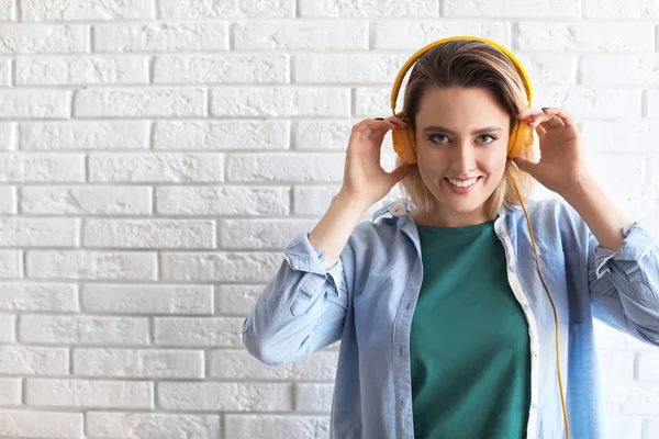 Πορτρέτο της όμορφης γυναίκας ακούγοντας μουσική με ακουστικά κοντά σε τοίχο τούβλο. Χώρος για κείμενο — Φωτογραφία Αρχείου