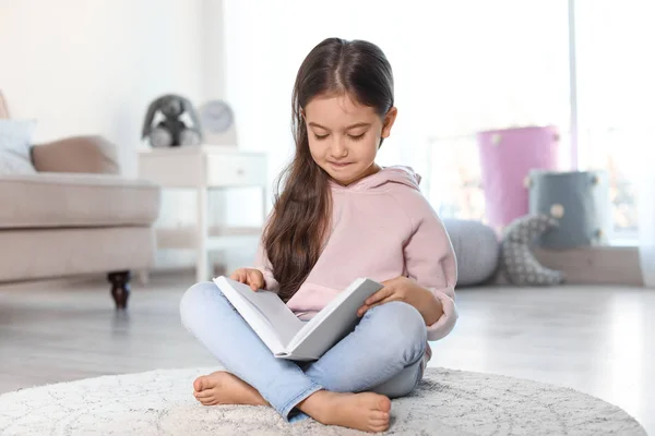 Niedliches Kind liest Buch auf dem Fußboden drinnen — Stockfoto