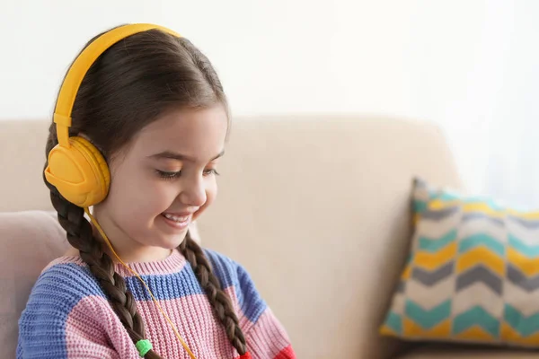 Criança bonito com fones de ouvido no sofá dentro de casa. Espaço para texto — Fotografia de Stock