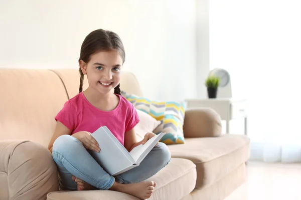 Χαριτωμένο παιδικό βιβλίο ανάγνωσης στον καναπέ σε εσωτερικούς χώρους — Φωτογραφία Αρχείου