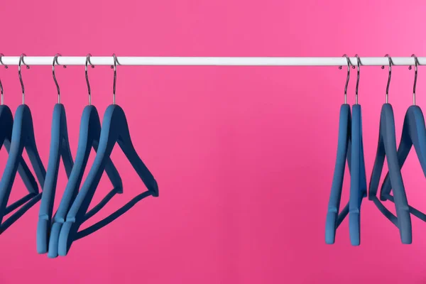 Metal rack with clothes hangers on color background, space for text — Stock Photo, Image