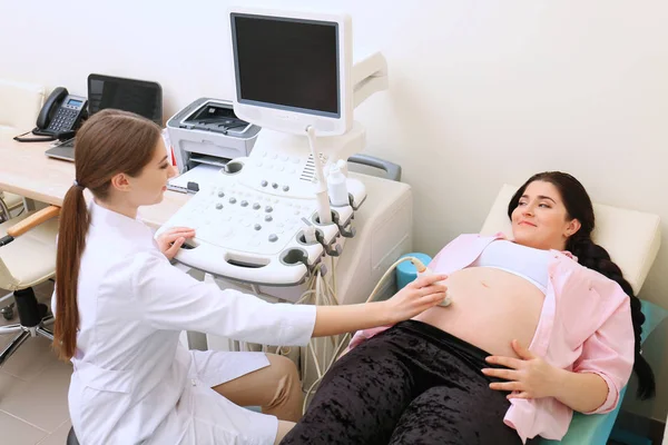 Ung, gravid kvinne som gjennomgår ultralydundersøkelse på klinikk – stockfoto