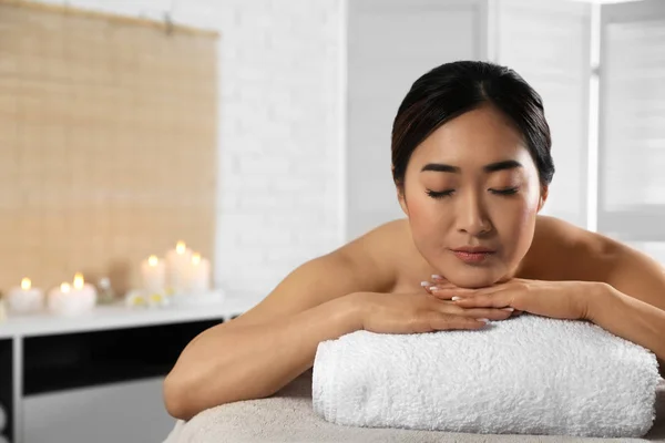 Bella donna asiatica sdraiata sul tavolo da massaggio nel salone spa. Spazio per testo — Foto Stock