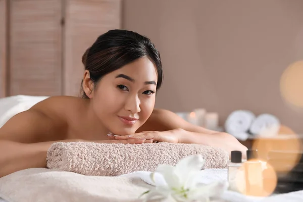 Hermosa mujer asiática tumbada en la mesa de masaje en el salón de spa. Espacio para texto — Foto de Stock