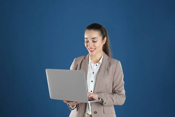 Potret wanita muda di kantor memakai laptop dengan latar belakang warna — Stok Foto