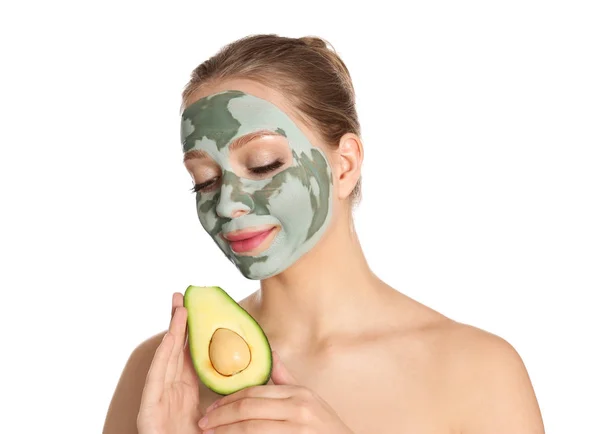 Bella donna che tiene avocado vicino al viso con maschera di argilla su sfondo bianco — Foto Stock