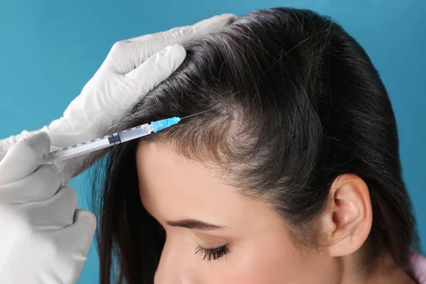 Jovem com problema de perda de cabelo recebendo injeção em fundo de cor, close-up — Fotografia de Stock