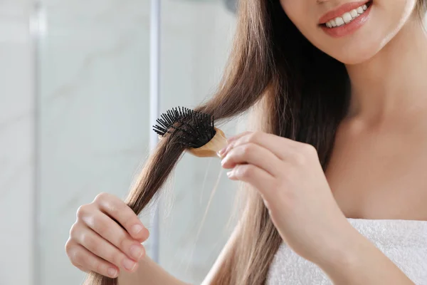 Young woman with hair brush in bathroom, closeup view — Stockfoto
