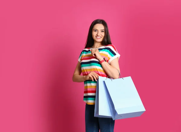 Schöne junge Frau mit leeren Papiertüten vor farbigem Hintergrund — Stockfoto