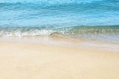 Güneşli bir günde deniz suyu ve plaj kumu manzarası