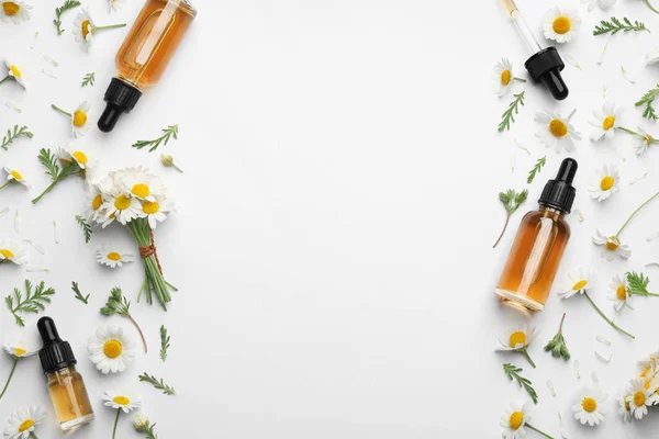 Flores de camomila e garrafas cosméticas de óleo essencial sobre fundo branco, vista superior. Espaço para texto — Fotografia de Stock