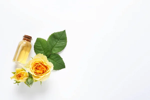 Fles Rose etherische olie en bloemen op witte achtergrond, bovenaanzicht — Stockfoto