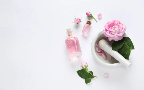 Composición con aceite esencial de rosa y flores sobre fondo blanco, vista superior —  Fotos de Stock