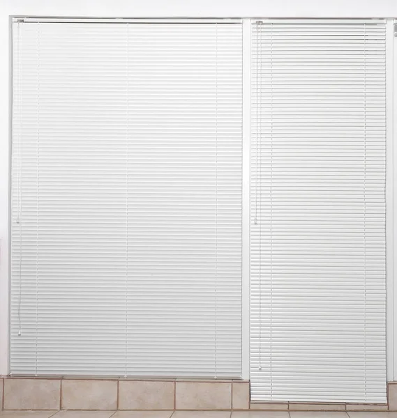 Okno z zamkniętymi białymi roletami poziomymi wewnątrz — Zdjęcie stockowe