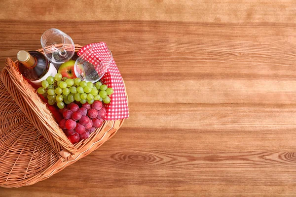 Picknickkorb mit Wein, Gläsern und Trauben auf Holztisch, Draufsicht. Raum für Text — Stockfoto