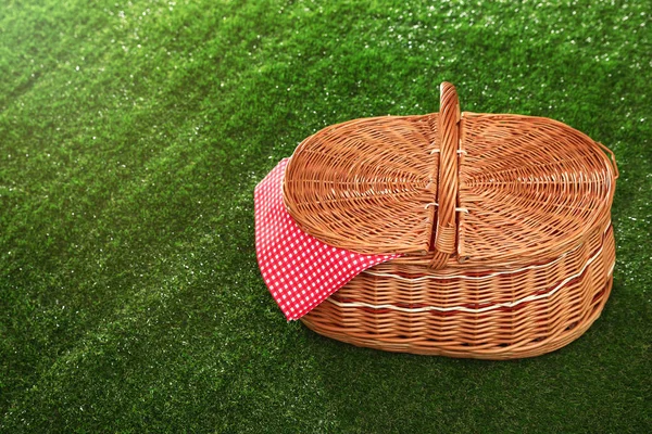 Закрытая корзина для пикника с салфеткой на траве, место для текста — стоковое фото