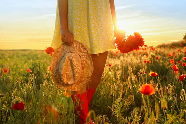 Wanita dengan topi jerami dan karangan bunga poppy di lapangan yang diterangi matahari, menutup — Stok Foto