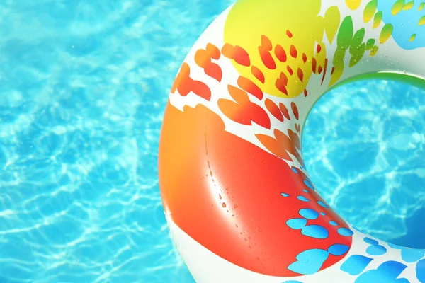 Anillo inflable colorido flotando en la piscina en el día soleado. Espacio para texto — Foto de Stock