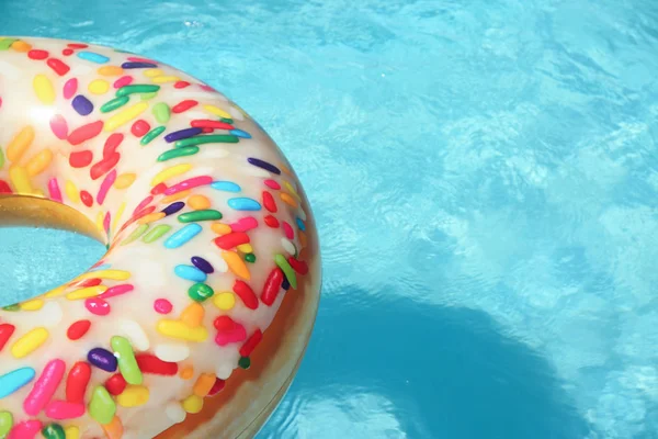 Anneau de beignet gonflable lumineux flottant dans la piscine le jour ensoleillé. Espace pour le texte — Photo