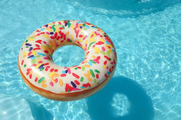 Anneau de beignet gonflable lumineux flottant dans la piscine le jour ensoleillé. Espace pour le texte — Photo