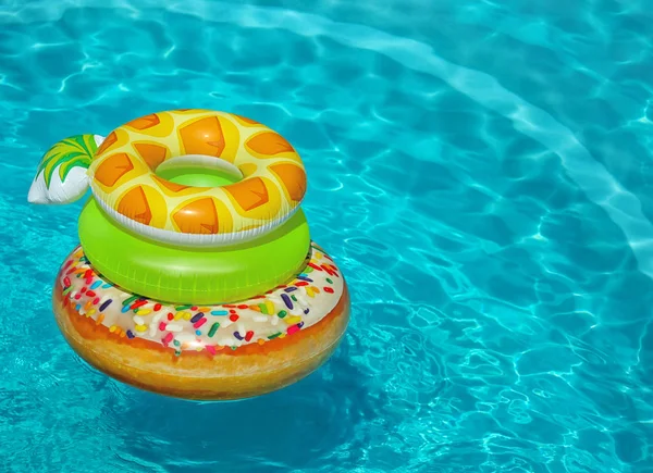 Pilha de anéis infláveis coloridos flutuando na piscina no dia ensolarado. Espaço para texto — Fotografia de Stock