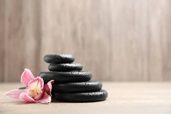 Stapel schwarzer Wellness-Steine mit Blume auf Holzgrund. Raum für Text — Stockfoto