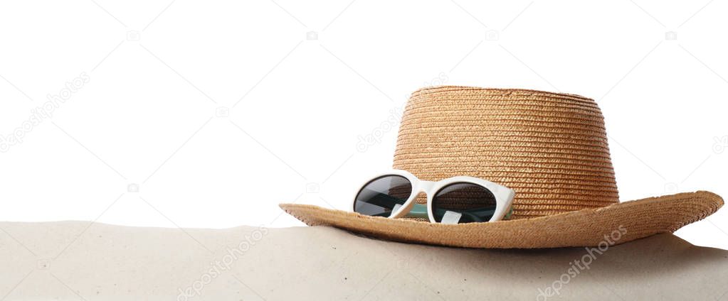 Hat and sunglasses on sand against white background, space for text. Stylish beach accessories