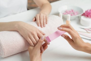 Manikürcü masada tampon ile müşterinin tırnaklarını parlatma, closeup. Spa tedavisi