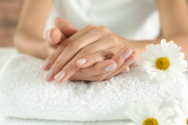 Yumuşak elli ve havlunun üzerinde çiçekler olan bir kadın, yakın plan. Spa tedavisi