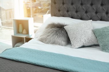 Farklı yastıklar ve hafif odada ekose ile rahat yatak. İç dekor için fikir