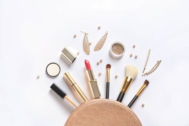 Beyaz arka planda kozmetik çanta ve farklı lüks makyaj ürünleri, üst görünüm