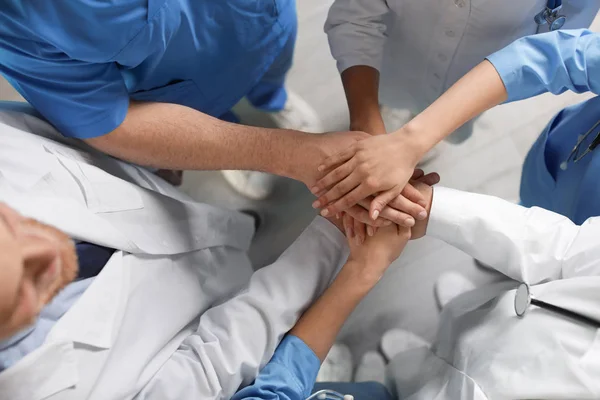 Jonge artsen brengen handen samen binnenshuis, bovenaanzicht. Unity concept — Stockfoto