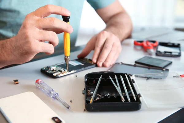 Technicien réparer téléphone portable à table, gros plan — Photo